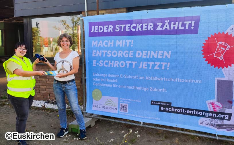 Ein Baustellen-Plakat mit der Überschrift "Mach mit! Entsorge deinen E-Schrott jetzt!". Daneben zwei Frauen die E-Schrott weiterreichen.